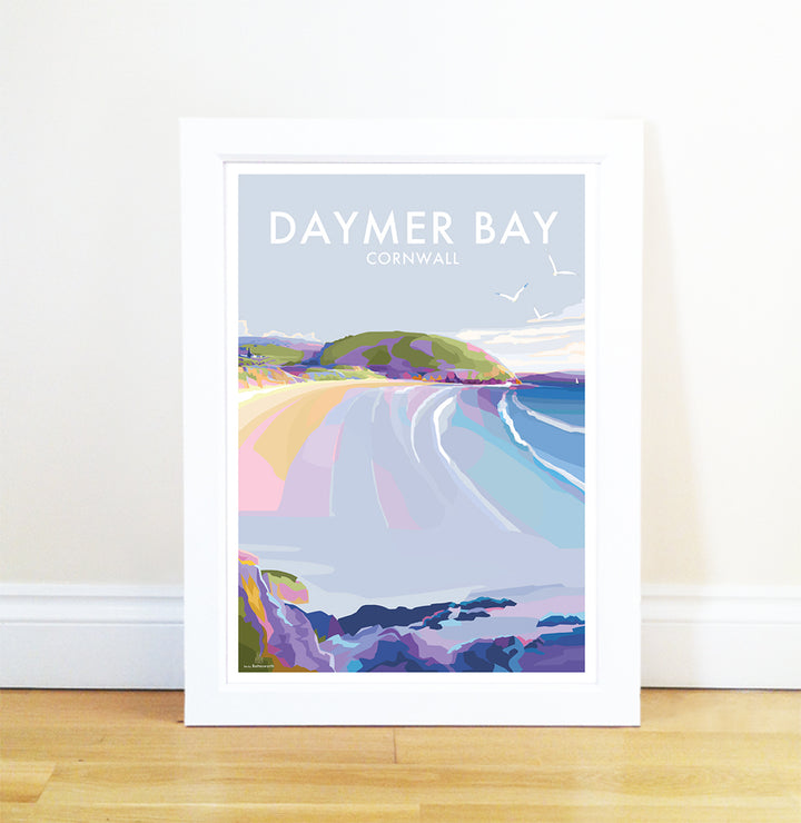 Framed print Daymer Bay by Becky Bettesworth features a vibrant, stylized seaside scene with waves, sandy beach, cliffs, and seagulls. Resting against a white wall on a wooden floor, it captures the essence of the Camel Estuary.