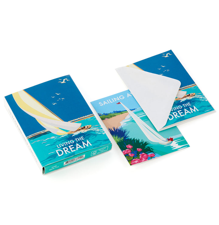 The BeckyBettesworth Living the Dream Notelet Miniboxes set showcases a sailing theme with recycled cards. The box depicts a sailboat on water, while an incomplete notelet and piece share the seaside image, blending tranquility with eco-friendly artistry.
